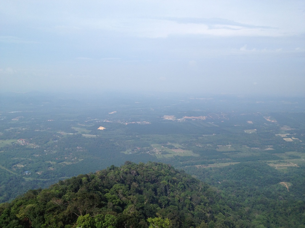 View from the boulder to the south-west. in the foreground is the main road, N111. Behind that, in the midground is the train tracks. Further behind is the North-south highway. Far in the horizon should be the Malacca straits, though not visible here. But the Linggi river can be just about seen in the middle of the picture, leading away to the straits